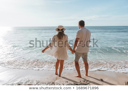 Stockfoto: Happy Young Romantic Couple Relaxing On The Beach And Watching The Sunset