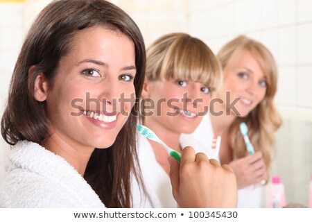 [[stock_photo]]: Three Female House Mates Brushing Their Teeth