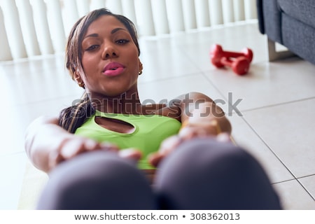 [[stock_photo]]: Home Fitness Black Woman Trains Abs And Looks At Camera