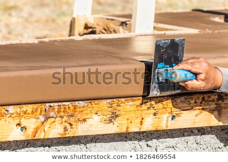 Stok fotoğraf: Construction Worker Using Stainless Steel Edger On Wet Cement Fo