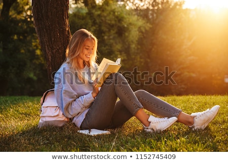 Stok fotoğraf: Portrait Of A Beautiful Young Female Student Sitting Outdoor At