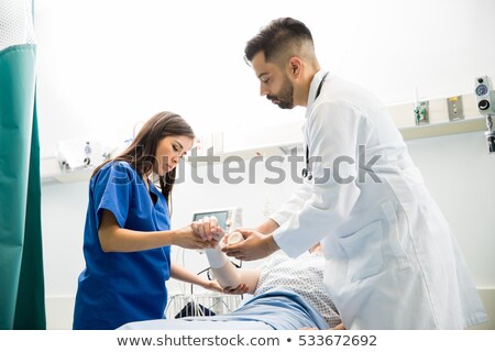 Zdjęcia stock: Brunette Nurse Putting Bandage On Arm Of Female Patient