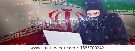 Stock photo: Criminal Young Man In Balaclava Standing And Using Laptop