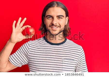 Foto stock: Happy Young Man With Toothy Smile Holding Ripe Red Apple In Right Hand