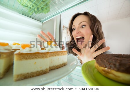 Stock fotó: Happy Young Woman Looking At Donut From Refrigerator