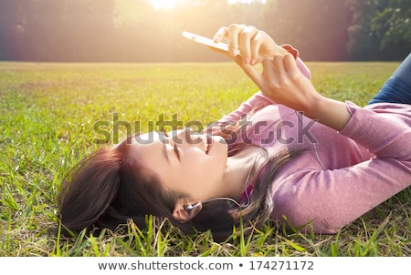 Stockfoto: Woman Lying In Meadow Phoning Mobile