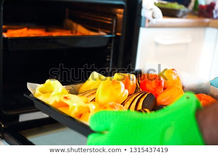 Foto stock: Close Up Shot Of Roast Pepper And Eggplant In A Tray A Man Is H