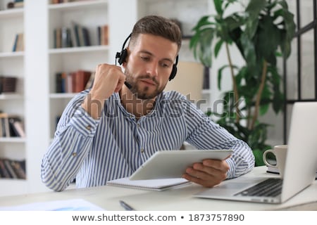 Stok fotoğraf: Happy Young Operator In Headphone Using Digital Tablet While Looking At You