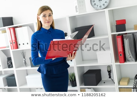 Сток-фото: A Young Girl In The Office Is Standing Near The Shelter And Scrolls Through The Folder With The Docu