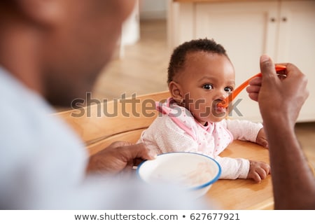 Stockfoto: Father Feeding Baby In Highchair At Home