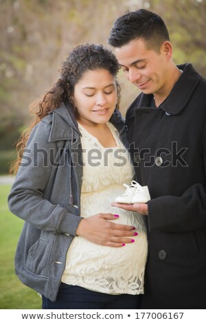 Foto stock: Hispanic Pregnant Couple Holding Baby Shoes