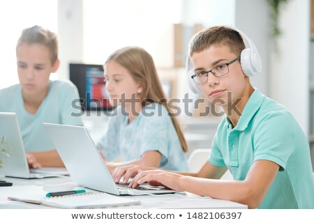 Handsome Schoolboy In Headphones Looking At You While Typing On Laptop Keypad Foto stock © Pressmaster