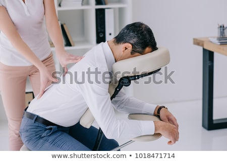 Foto stock: Masseuse Massaging Back Of Client Massage Chair