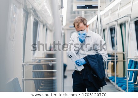 Foto stock: Infected Man Wears Medical Mask Has Constant Coughing Symptoms Of Covid 19 Holds Rolled Up Newspa