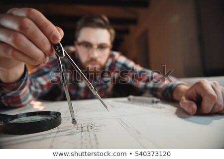 Imagine de stoc: Young Bearded Man Working With Compass And Graph At Office