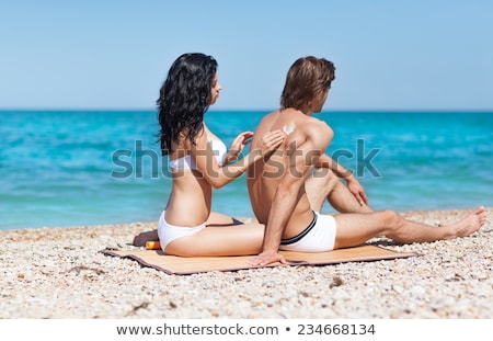 Stok fotoğraf: Woman Putting Sun Screen On Back Of Man