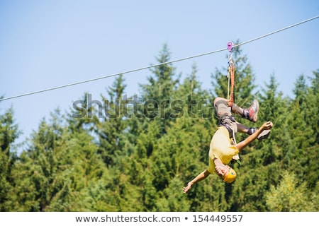 Stock fotó: Man Hanging Upside Down On Zip Line