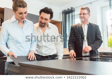 Foto stock: Salesman Explaining Details Of New Kitchen To Couple