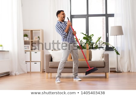 [[stock_photo]]: Man With Broom Cleaning And Singing At Home
