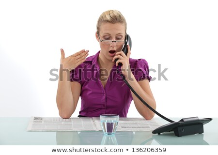 Foto stock: Surprised Woman Reading A Newspaper Whilst On The Phone