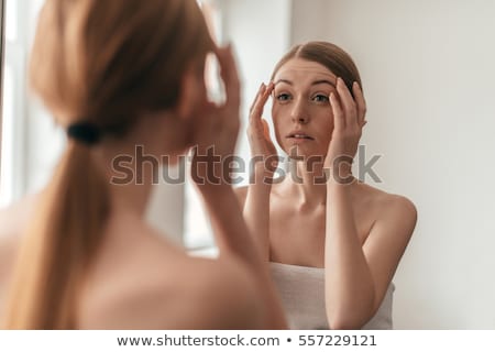 Foto stock: Redhead Woman Looking At Her Reflection In Mirror