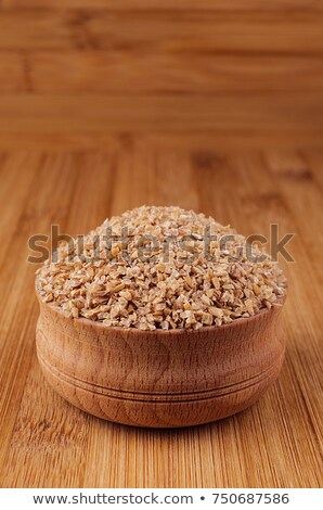 Foto stock: Wheat Groats In Wooden Bowl On Brown Bamboo Board Closeup