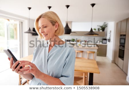 Stok fotoğraf: Person Using Cellphone To Adjust Temperature Of Thermostat