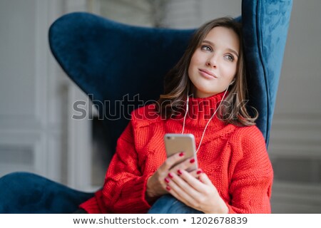 Stockfoto: Pensive Cute Female Feels Relaxed Listens Pleasant Music In Playlist Holds Cellular Looks With Dr