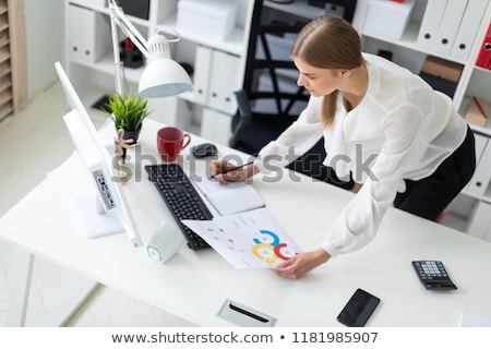 Stock fotó: A Young Girl Stands Bent Near A Table In The Office The Girl Works With A Computer Notepad And Doc