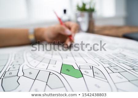 Foto stock: Human Hand Holding Pencil Over Cadastre Map