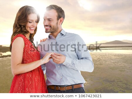 Stockfoto: Couple Engaged Against River In Evening With Flare