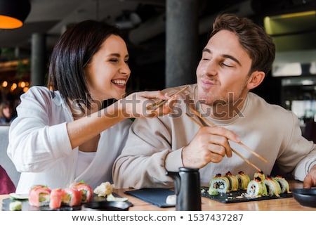 [[stock_photo]]: Smiling Couple Eating Sushi Rolls At Restaurant