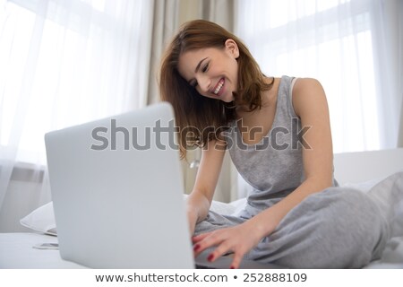 Stock foto: Beautiful Young Woman In Pajamas Sitting On Bed With Laptop