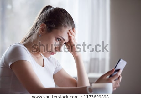Stok fotoğraf: Young Woman Reading Sms Looking Annoyed