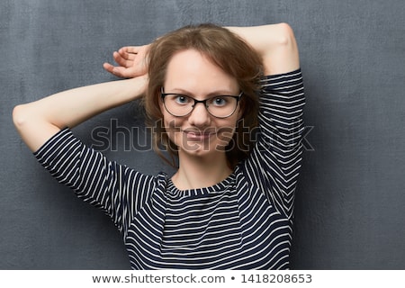 Stockfoto: Attractive Young Blonde Girl In Striped Blouse Smiling Holding Her Hair Standing On Gray Background