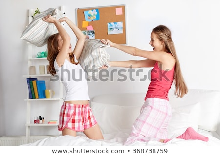 Foto d'archivio: Happy Teen Girl Friends Fighting Pillows At Home