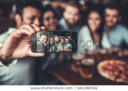 Stockfoto: Group Of Cheerful Young Friends Making Selfie In Cafe While Sitting By Table