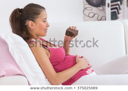 [[stock_photo]]: Emme · enceinte, · coucher · dans · lit, · à, · chocolats, · sourire