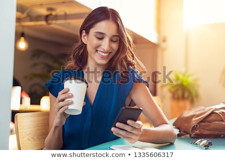 Stock photo: Young Woman Sitting Using A Mobile In A Cafeteria