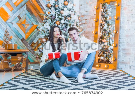 Сток-фото: Young Happy Family Near A Christmas Tree At Home Holding Gift An