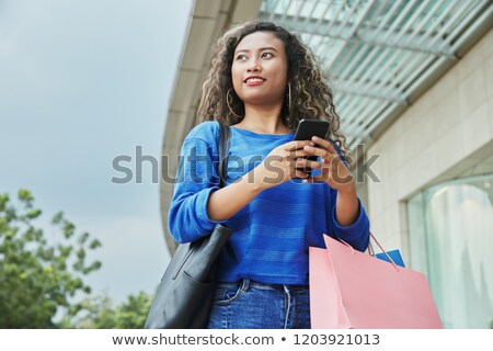 Stockfoto: Indonesian Woman With Paper Bags Using Smartphone