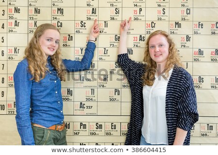 Stockfoto: Two Female Students Pointing At Periodic Table In Chemistry Less