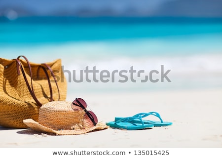 Foto stock: Straw Hat Flip Flops And Sunglasses On Beach Sand