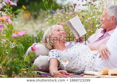 Foto stock: Side View Of Active Senior Couple Relaxing On Picnic Blanket At Beach