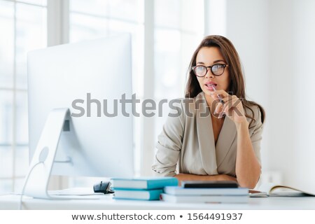 Stock foto: Contemplative Female Entrepreneur Keeps Pen In Mouth Focused In Monitor Of Computer Thinks On Deve