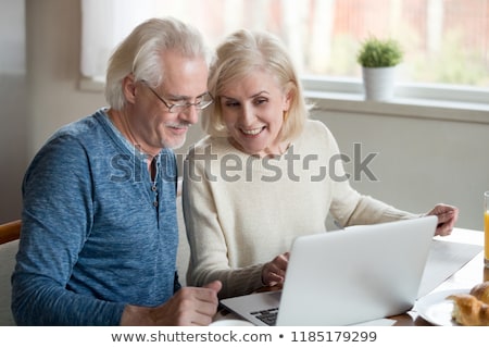 Stok fotoğraf: A Middle Age Couple Looking At A Laptop