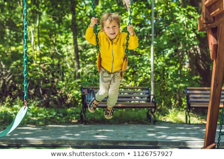 Zdjęcia stock: A Boy In A Yellow Sweatshirt Sits On A Swing On A Playground In Autumn