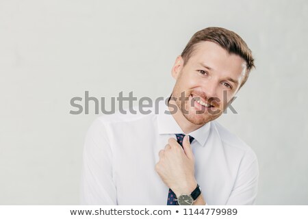 Stock fotó: Cheerful Unshaven Male Keeps Hand On Tie Dressed In Elegant White Shirt Smiles Friendly Happy To