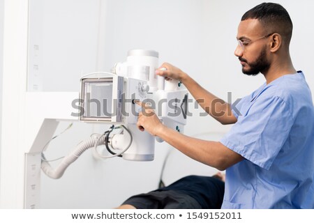 Stok fotoğraf: Young Mixed Race Man In Blue Uniform Pressing Button On New Medical Equipment