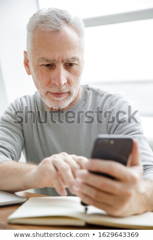 Stockfoto: Photo Of Serious Mature Man Making Notes And Typing On Cellphone